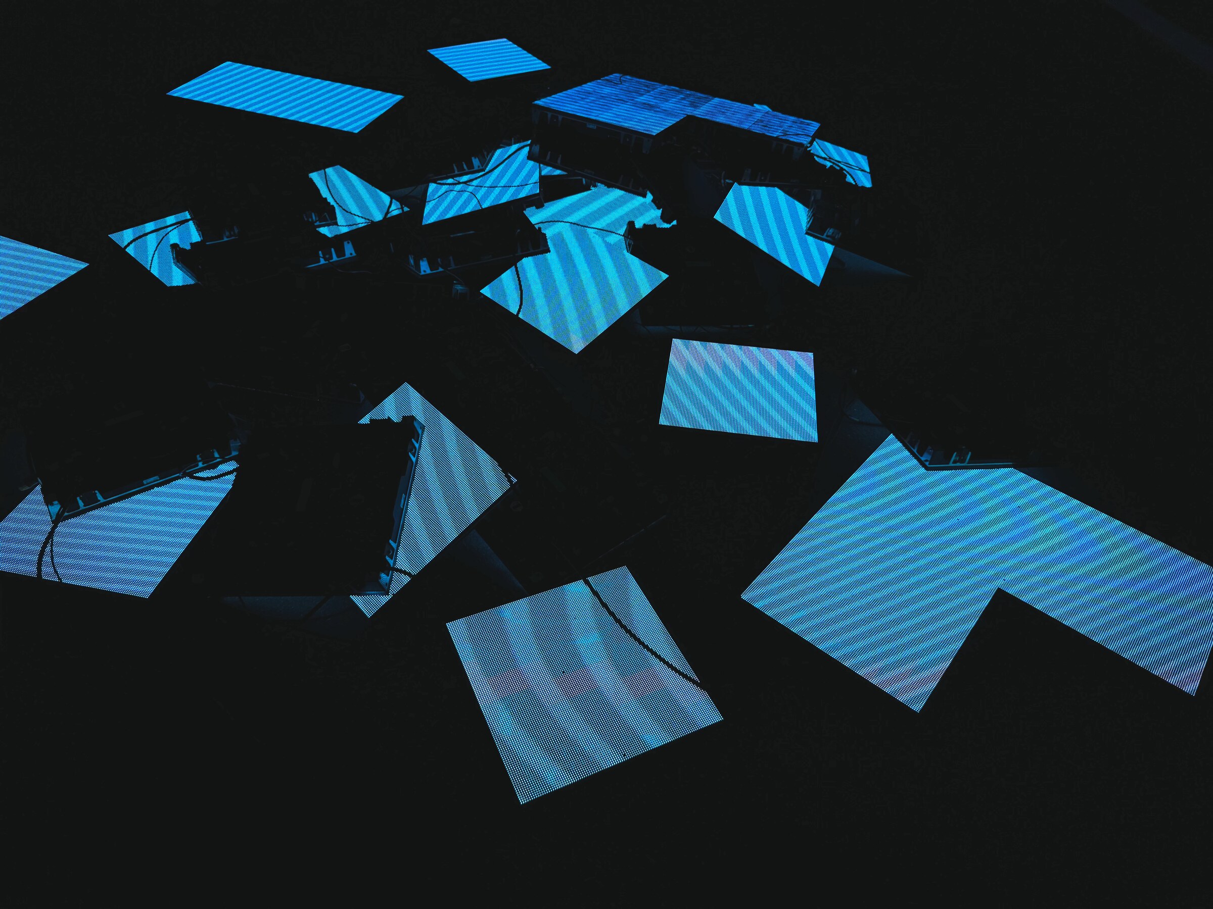 Blue geometric projection suspended over a dark crowd