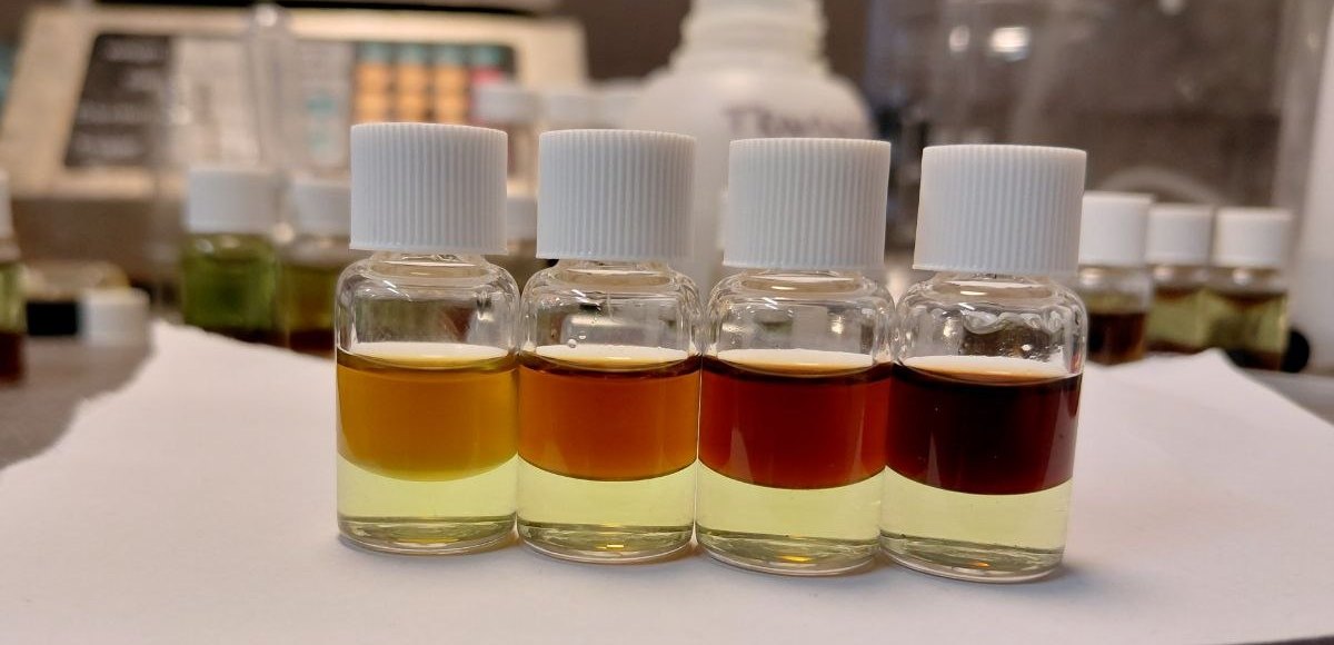 Four PRO Test for Cocaine Quantity reference vials in a lab, top layers from orange at 25% cocaine to near black at 100%