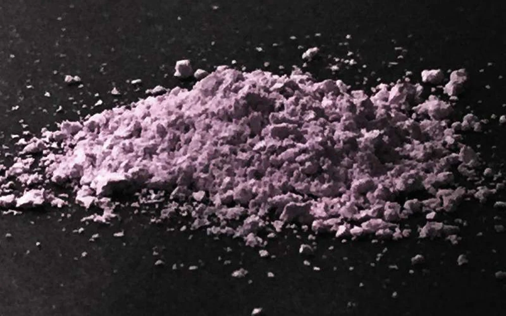 Lilac pink 2C-B powder in a small heap on a black surface