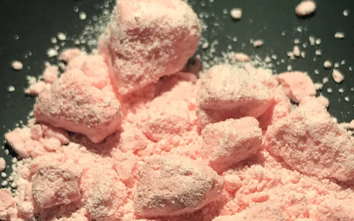 Pink amphetamine chunks and loose pink powder on a dark surface