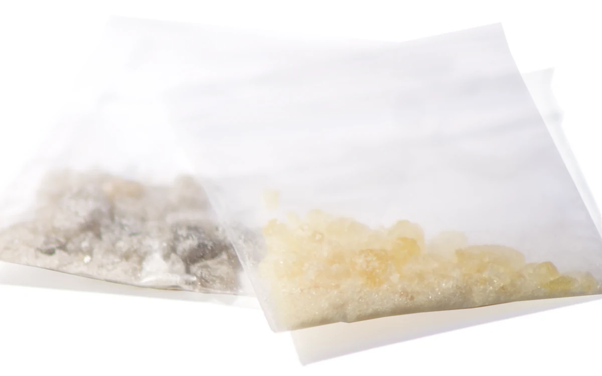 Two bags of MDMA crystals side by side, one grey and one yellow