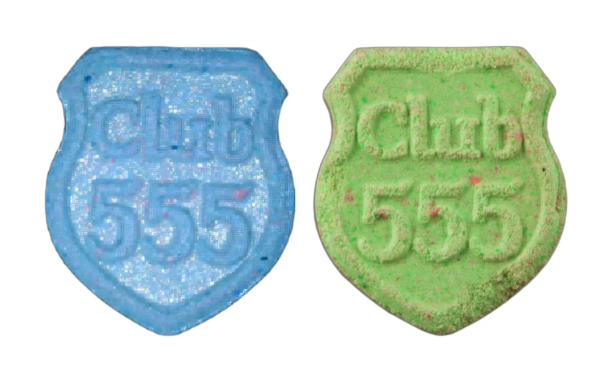 Two Club 555 shield shaped pills side by side, one blue and one green