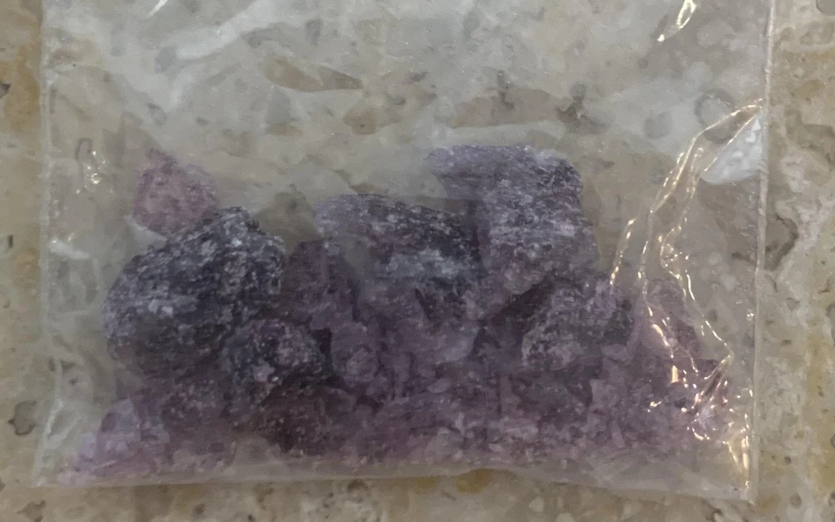 Violet and purple MDMA crystal chunks inside a small clear bag