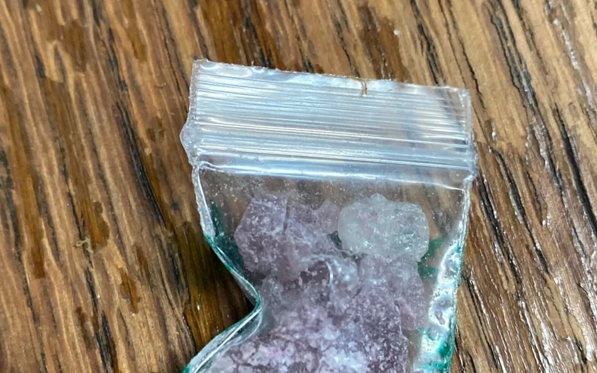 A bag of MDMA crystal showing both purple and teal green tints
