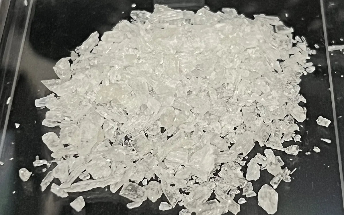 A heap of clear and white methamphetamine crystal shards in a clear container