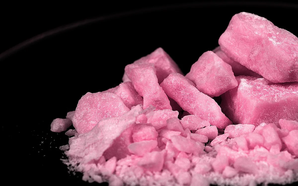Bright pink methamphetamine chunks photographed against a black background