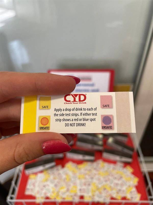 Eine Person hält eine CYD-Testkarte über einem Kartenfach an einer Universitätsausgabestelle
