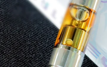 Amber cannabis oil visible through the glass tank of a vape cartridge