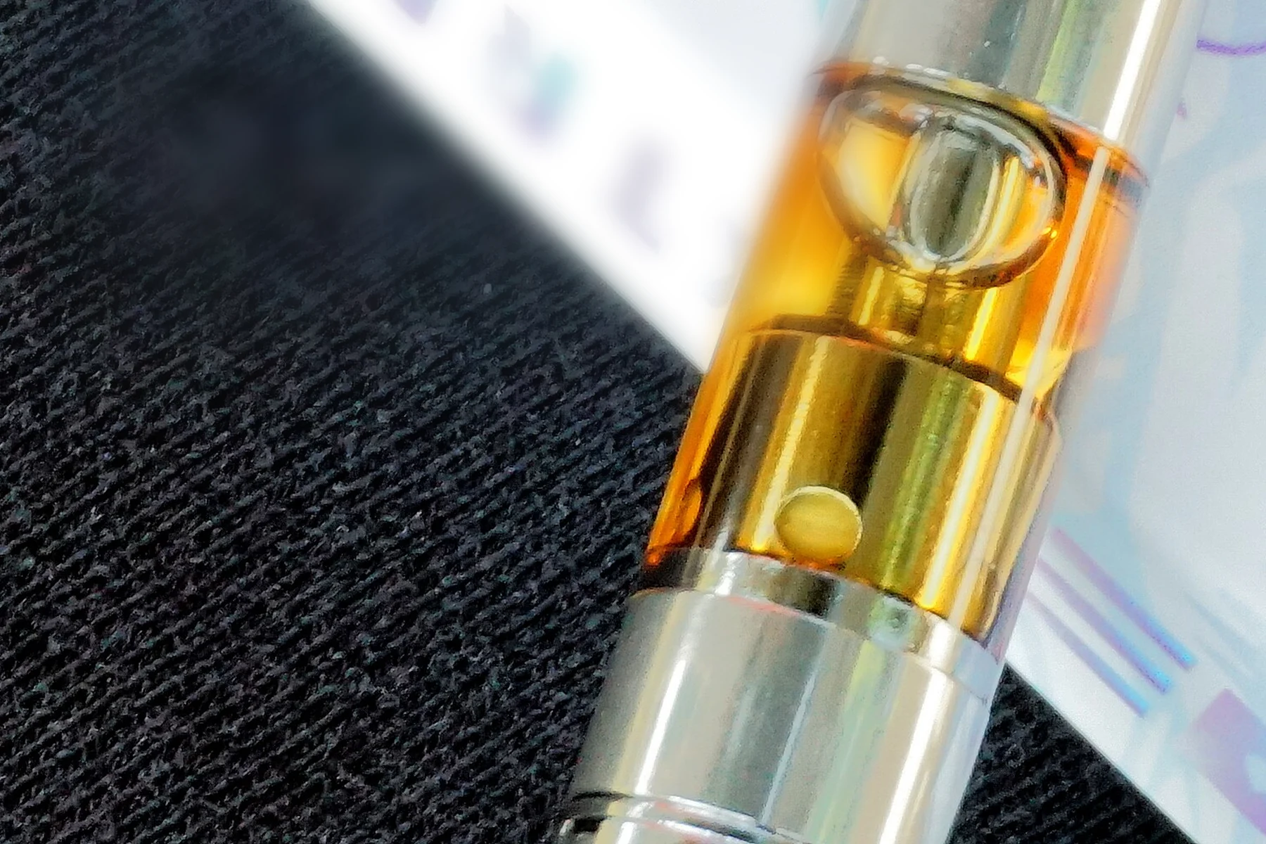 Amber cannabis oil visible through the glass tank of a vape cartridge